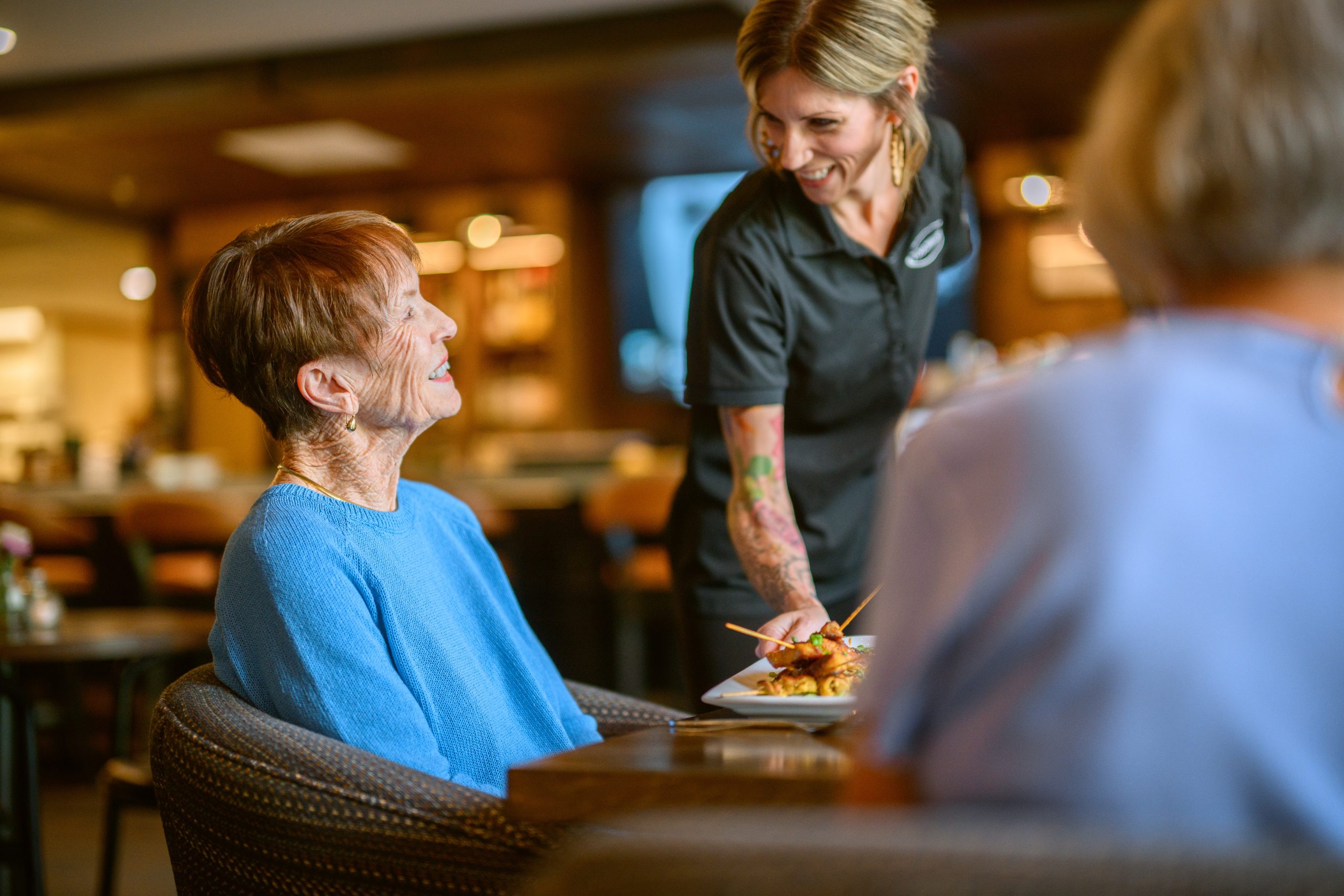 Resident being served dinner by Touchmark team member
